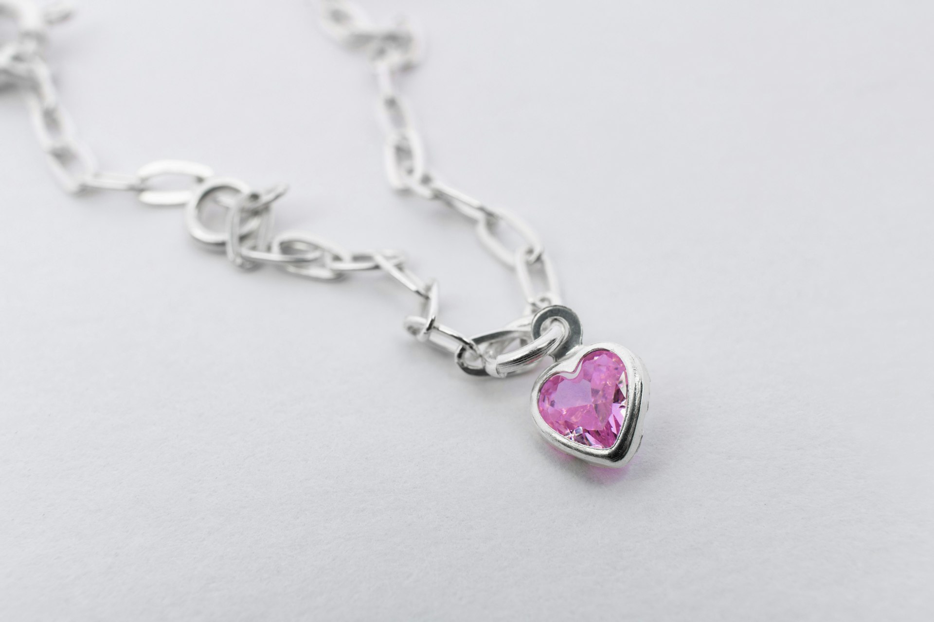 a pink heart shaped pendant on a silver chain